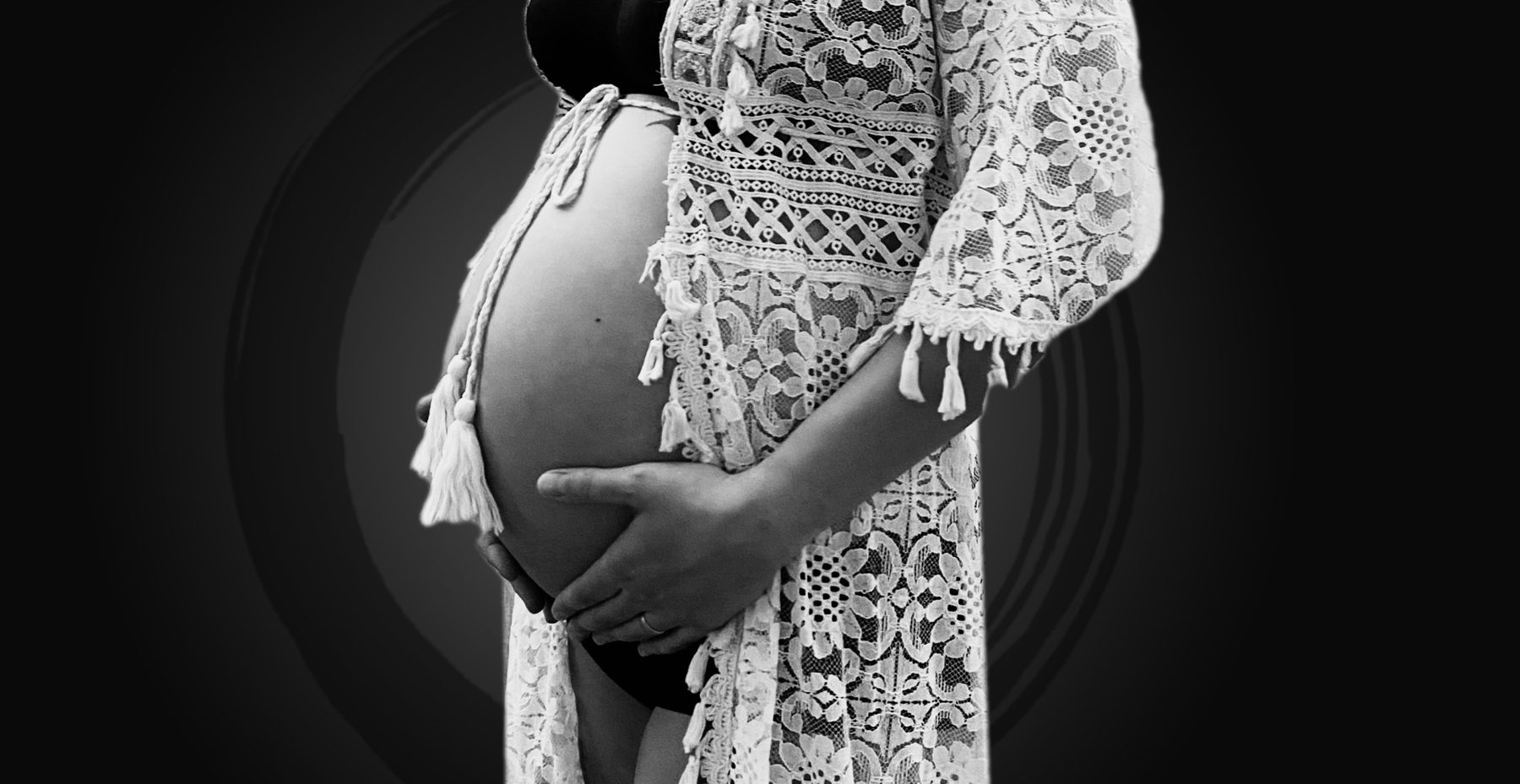 Schwangere Frau im Profil, die Hände am Bauch